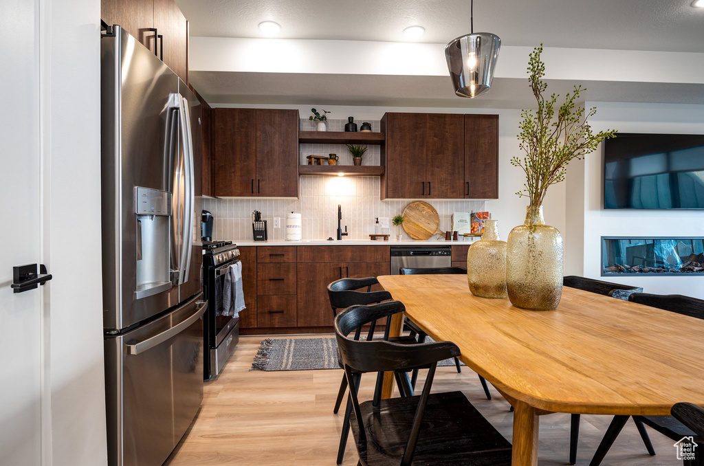 Kitchen featuring backsplash, stainless steel appliances, sink, light hardwood / wood-style flooring, and dark brown cabinets
