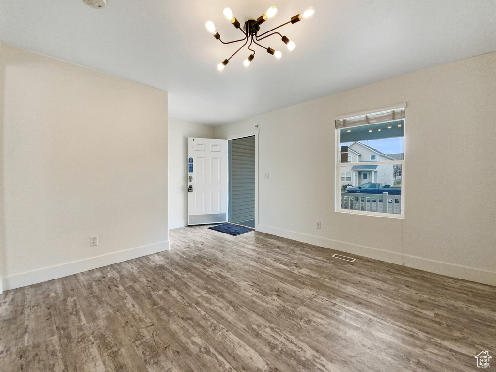 Empty room with a chandelier and hardwood / wood-style floors