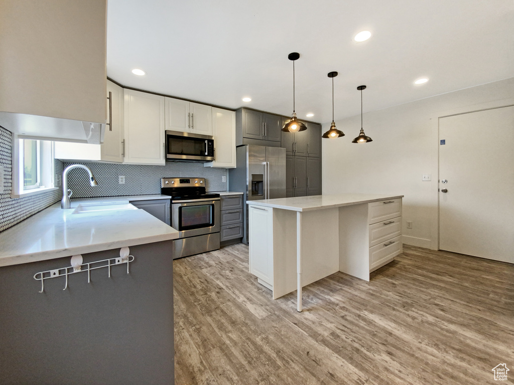 Kitchen featuring sink, light wood-type flooring, tasteful backsplash, and stainless steel appliances