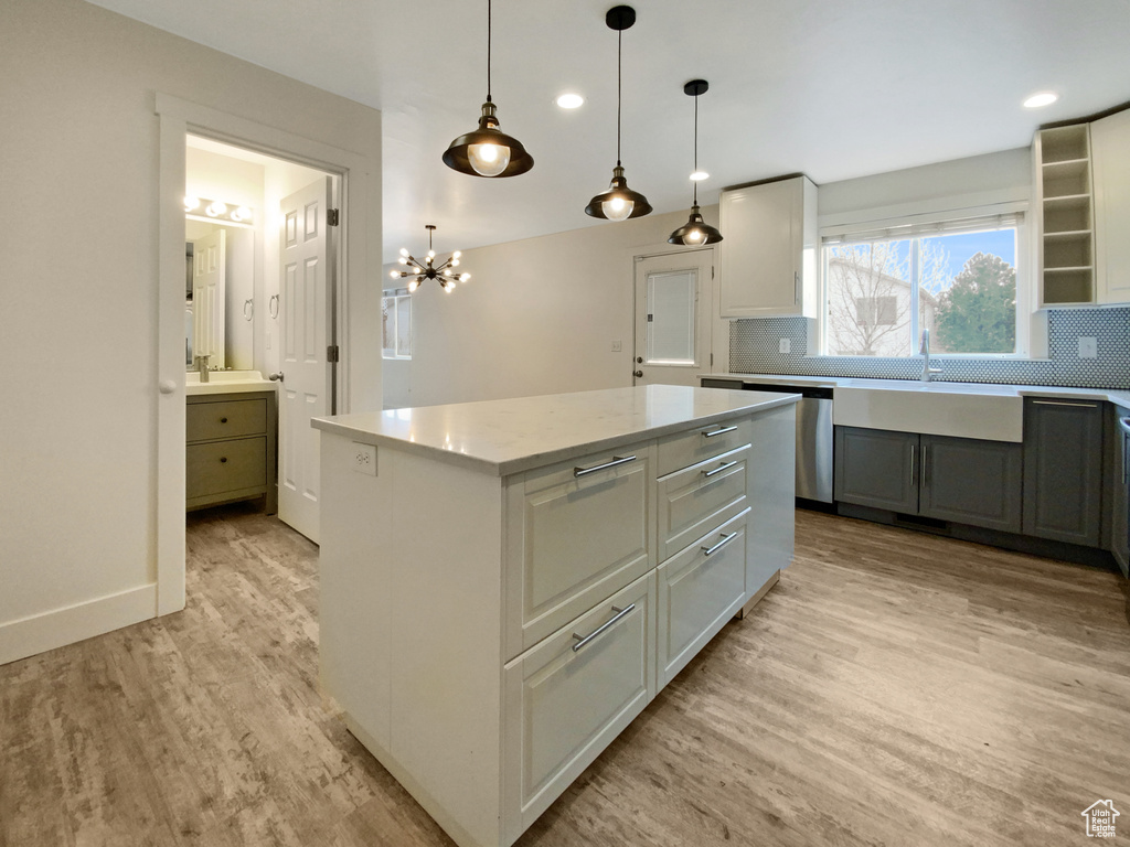 Kitchen with a kitchen island, light hardwood / wood-style flooring, pendant lighting, and backsplash