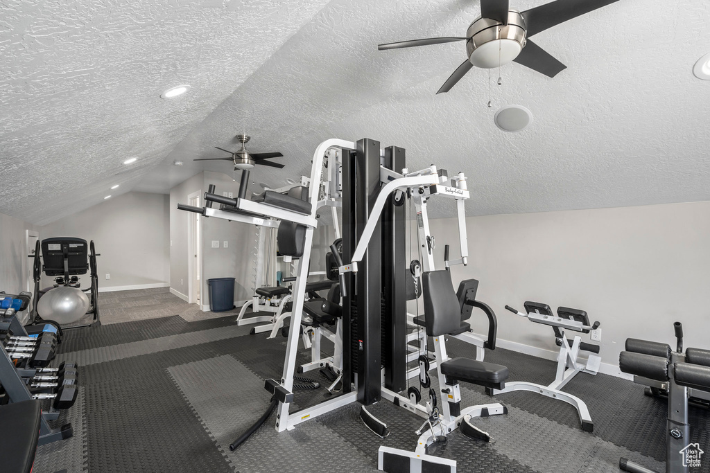 Gym featuring dark colored carpet, a textured ceiling, and ceiling fan