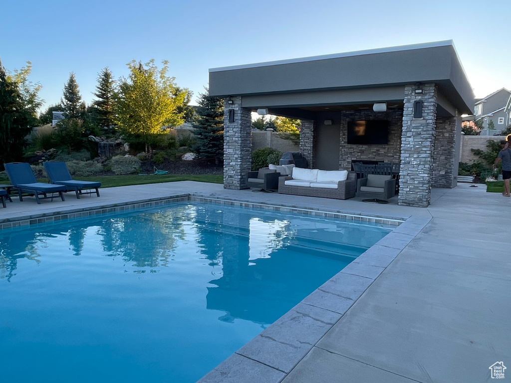 View of swimming pool featuring an outdoor living space with a fireplace and a patio