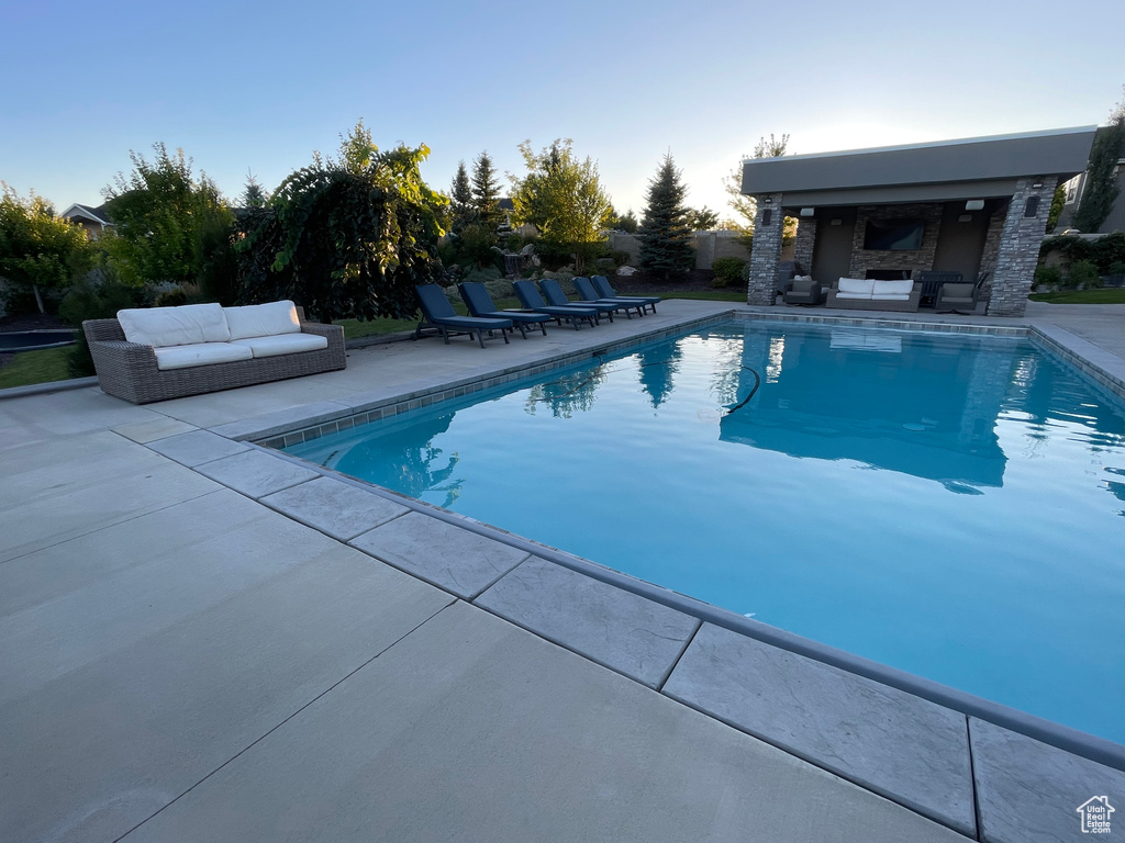 View of pool with a patio and an outdoor living space with a fireplace