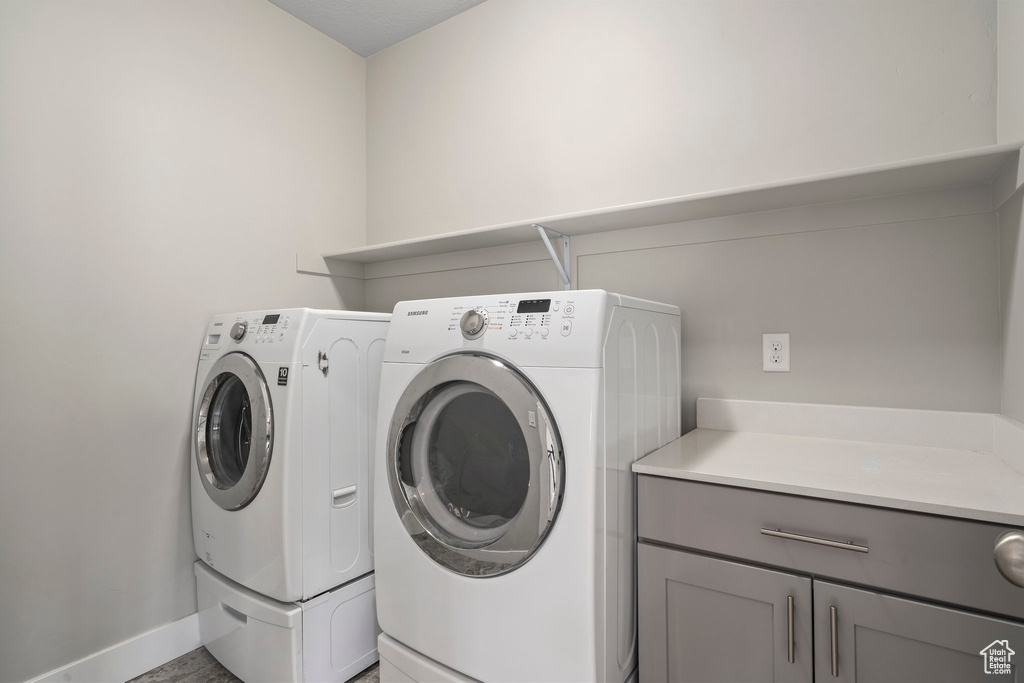 Clothes washing area featuring cabinets and independent washer and dryer