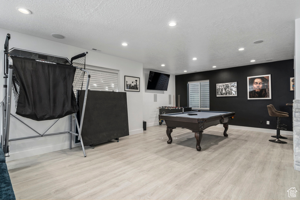 Recreation room featuring a textured ceiling, billiards, and light hardwood / wood-style flooring