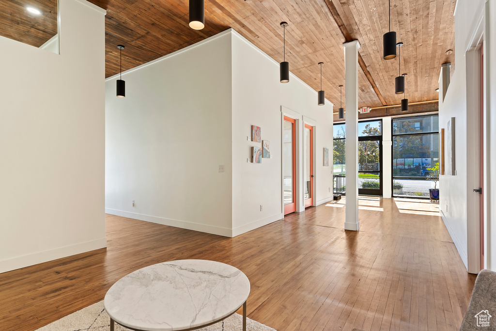 Interior space with a high ceiling, wood ceiling, a wall of windows, and hardwood / wood-style floors