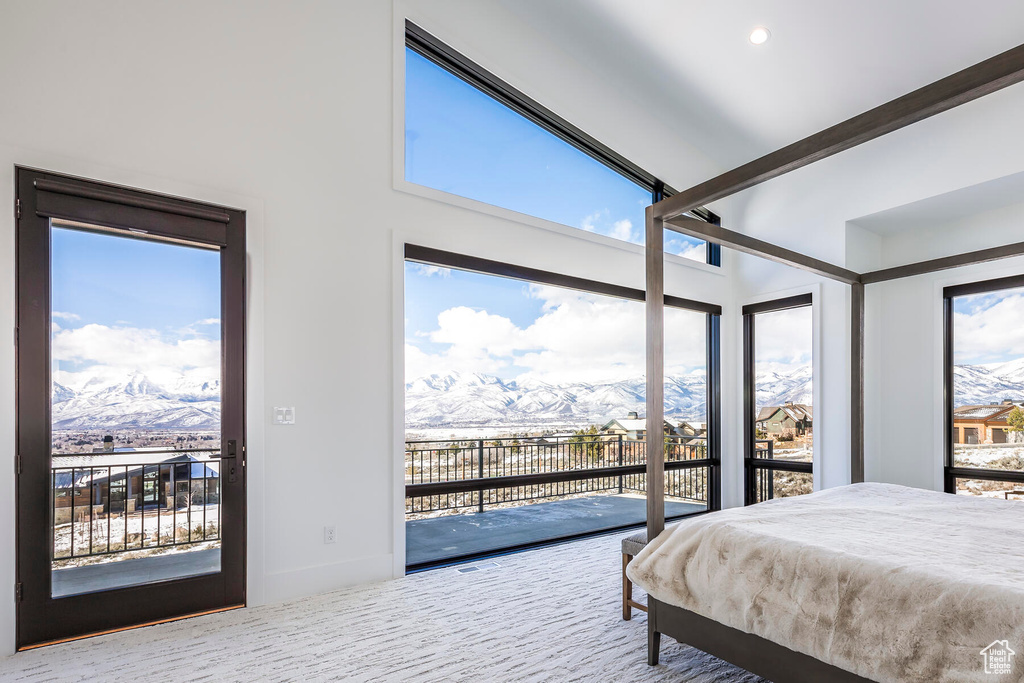 Carpeted bedroom with a mountain view, access to outside, and a high ceiling