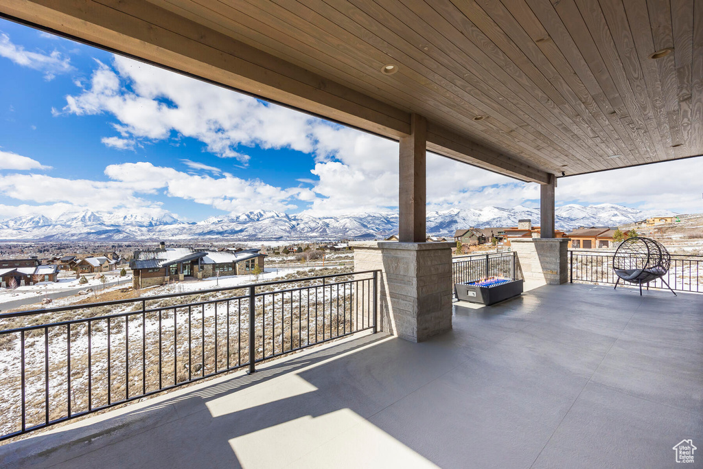 Snow covered patio featuring a balcony and a mountain view