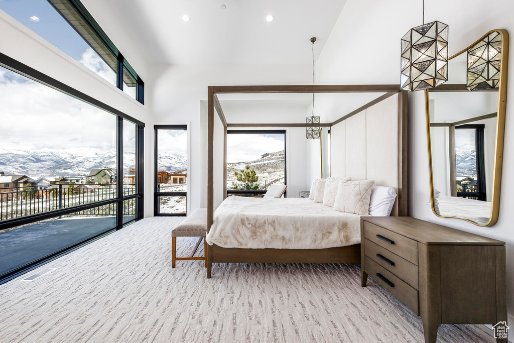 Carpeted bedroom featuring a mountain view, access to exterior, a high ceiling, and multiple windows