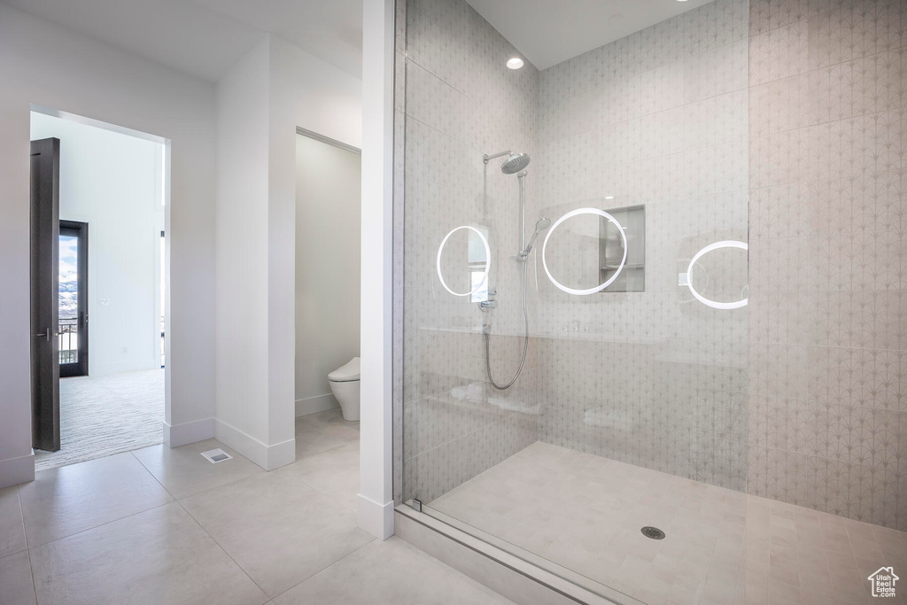 Bathroom featuring tile flooring, toilet, and tiled shower