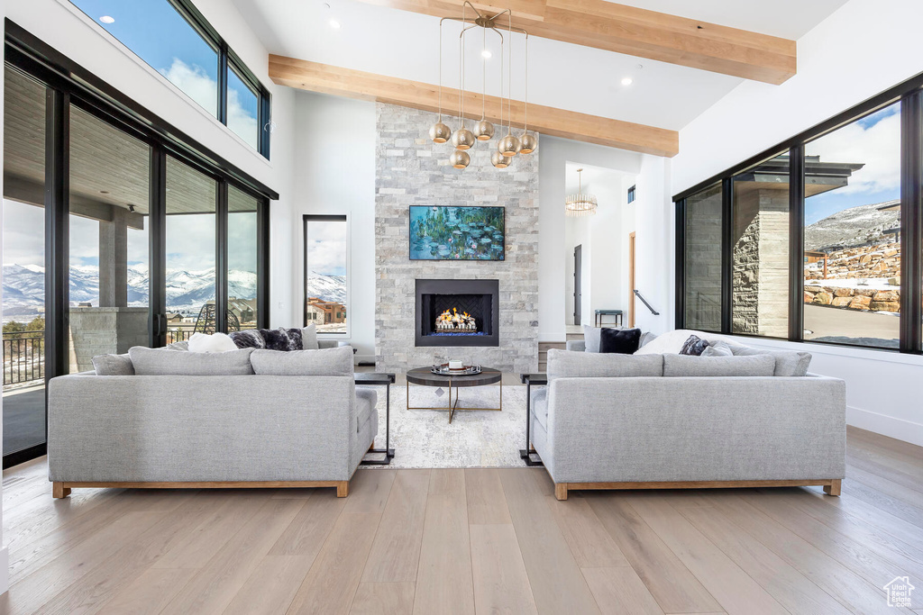 Living room featuring a stone fireplace, a mountain view, light hardwood / wood-style floors, and beam ceiling