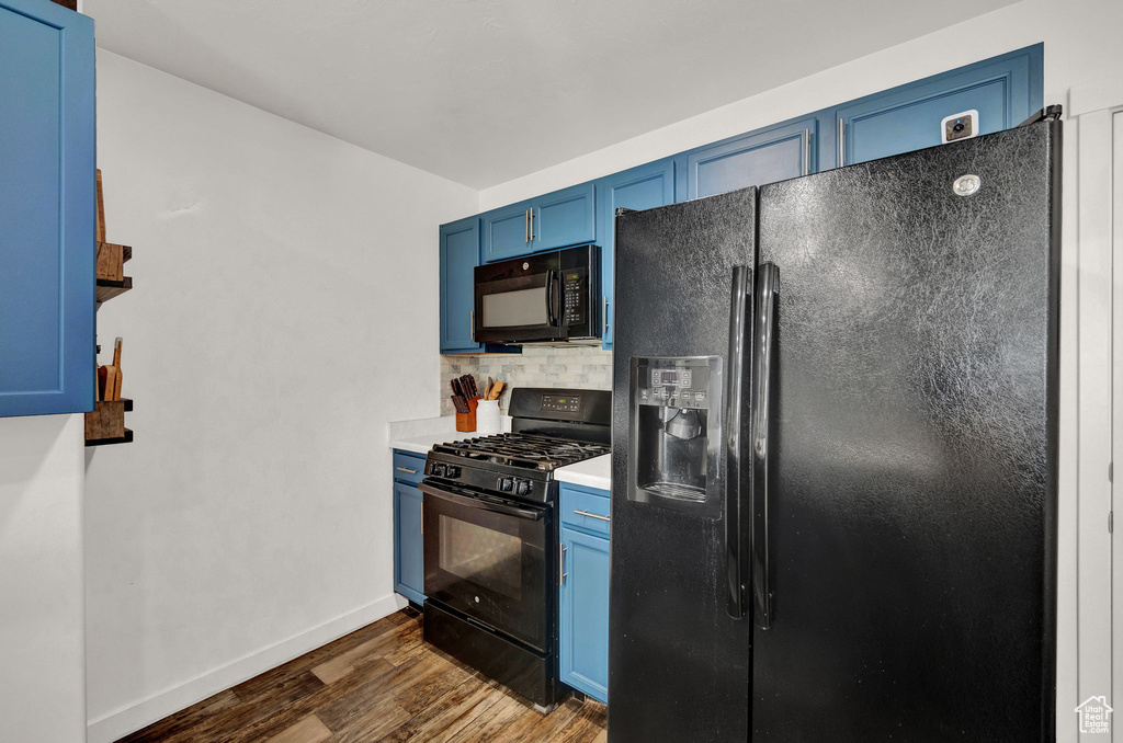 Kitchen featuring black appliances, blue cabinets, dark wood-type flooring, and backsplash