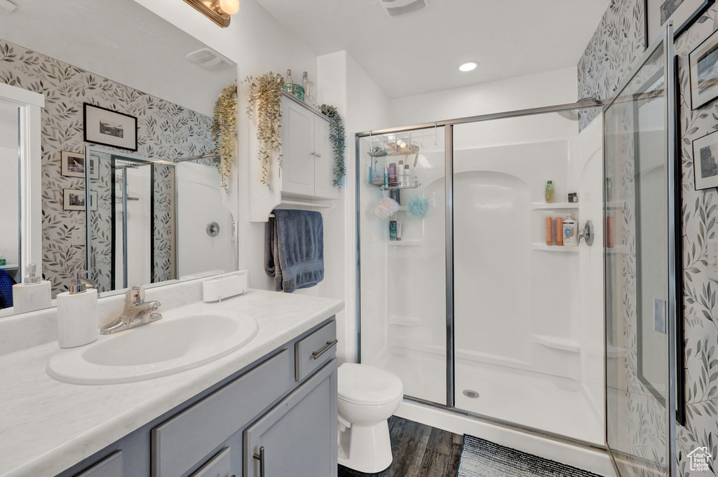 Bathroom featuring hardwood / wood-style flooring, toilet, walk in shower, and large vanity