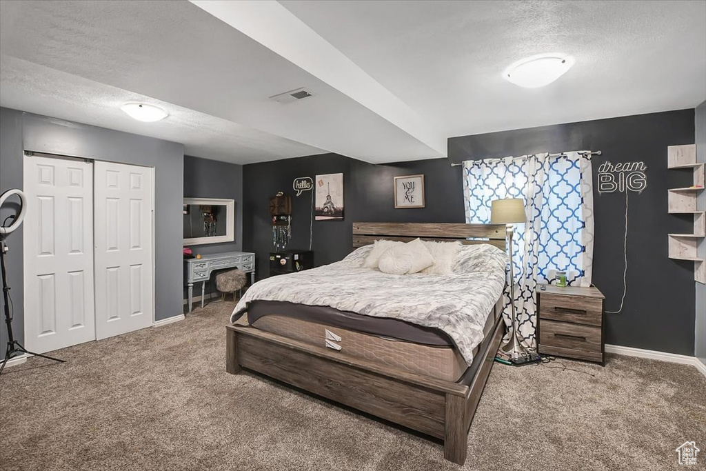 Bedroom with dark colored carpet, a closet, and a textured ceiling