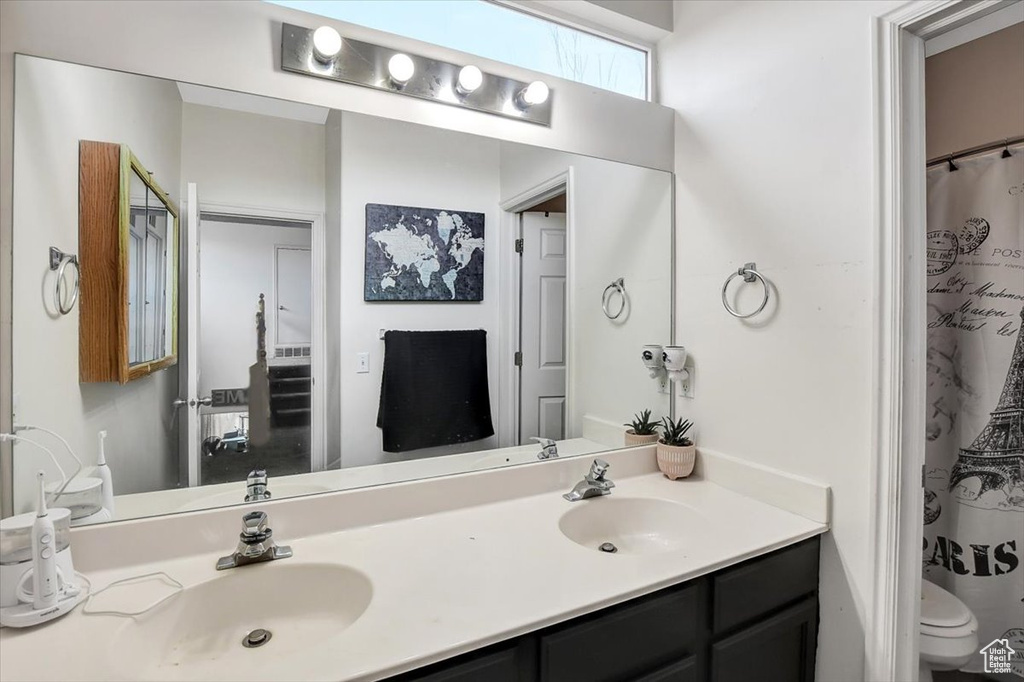 Bathroom featuring dual bowl vanity and toilet