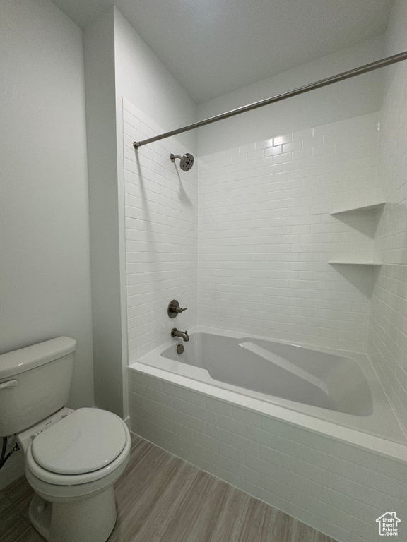 Bathroom with hardwood / wood-style flooring, toilet, and tiled shower / bath combo