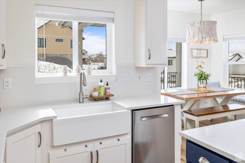 Kitchen featuring white cabinetry, decorative light fixtures, dishwasher, and sink