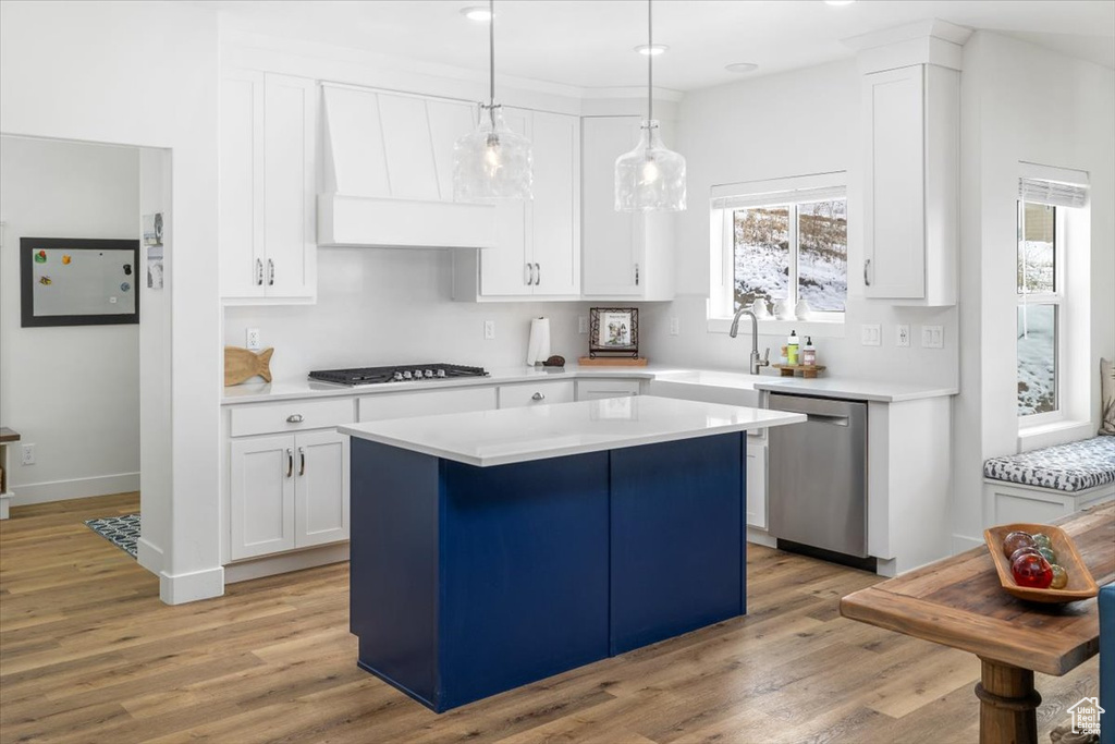 Kitchen with a center island, white cabinetry, dishwasher, and light hardwood / wood-style floors
