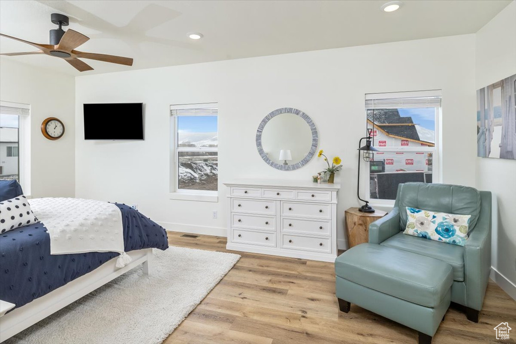 Bedroom with light hardwood / wood-style floors, multiple windows, and ceiling fan
