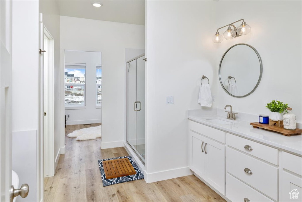 Bathroom featuring walk in shower, vanity, and hardwood / wood-style floors