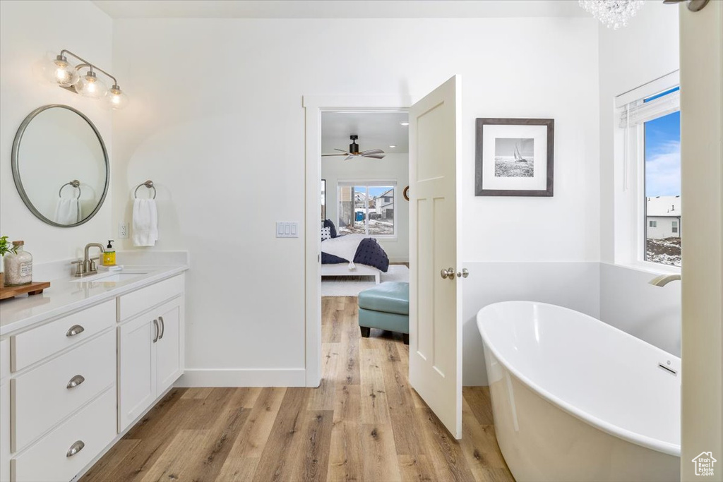 Bathroom featuring hardwood / wood-style flooring, a bathing tub, vanity, and ceiling fan
