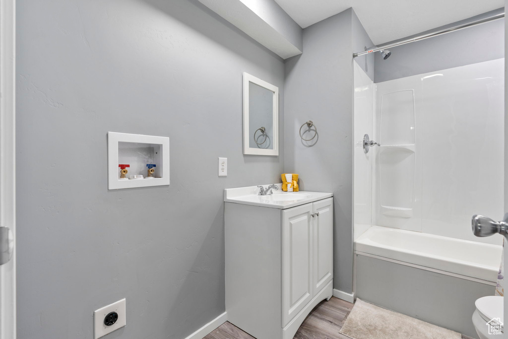 Full bathroom featuring toilet, hardwood / wood-style flooring, large vanity, and bathing tub / shower combination