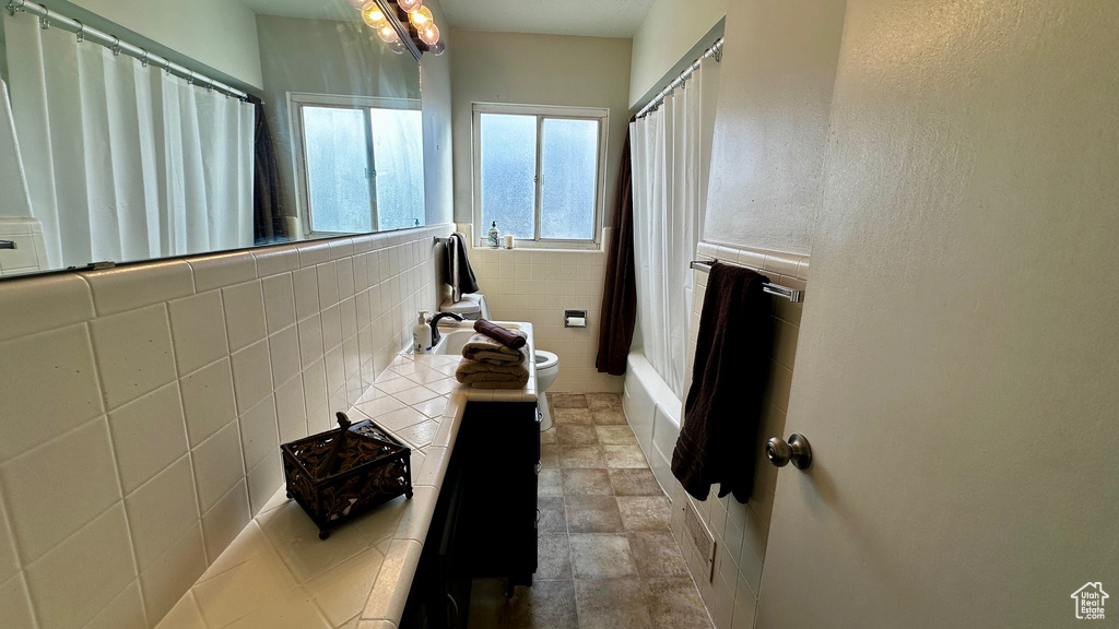 Full bathroom featuring a chandelier, toilet, tile flooring, backsplash, and shower / tub combo with curtain