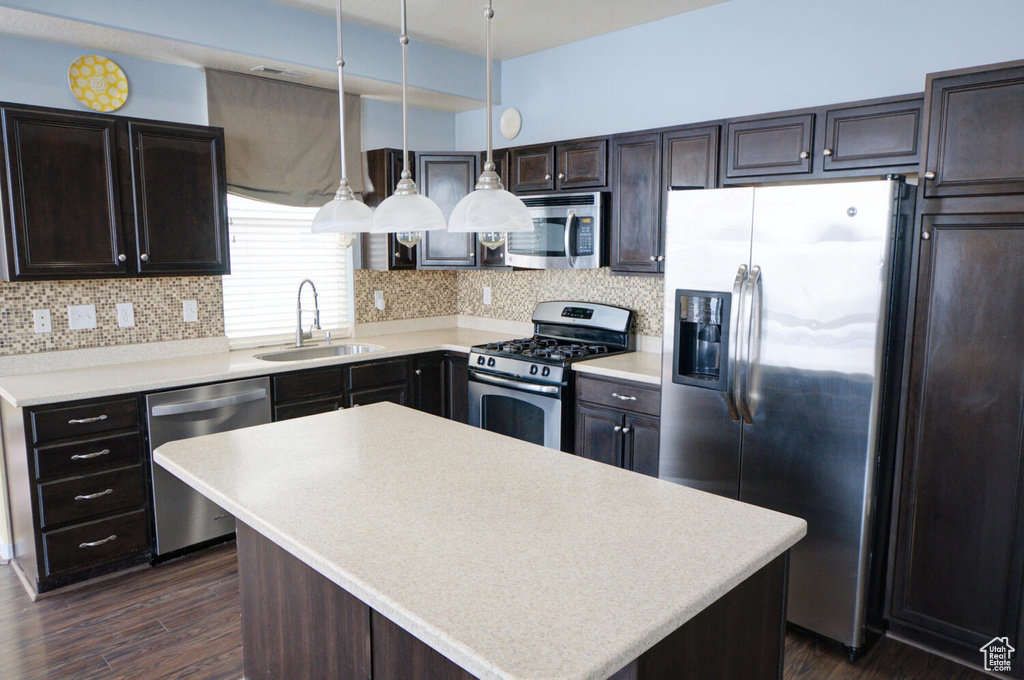 Kitchen featuring stainless steel appliances, dark hardwood / wood-style flooring, sink, pendant lighting, and a center island
