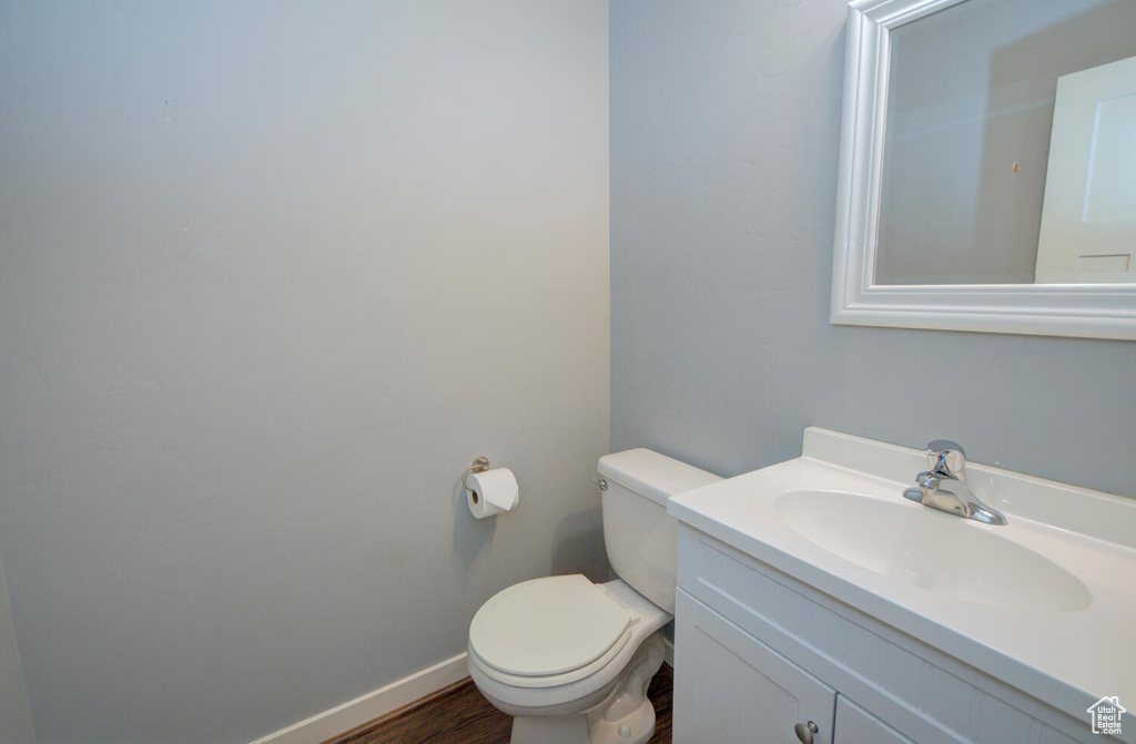 Bathroom featuring hardwood / wood-style flooring, toilet, and vanity with extensive cabinet space