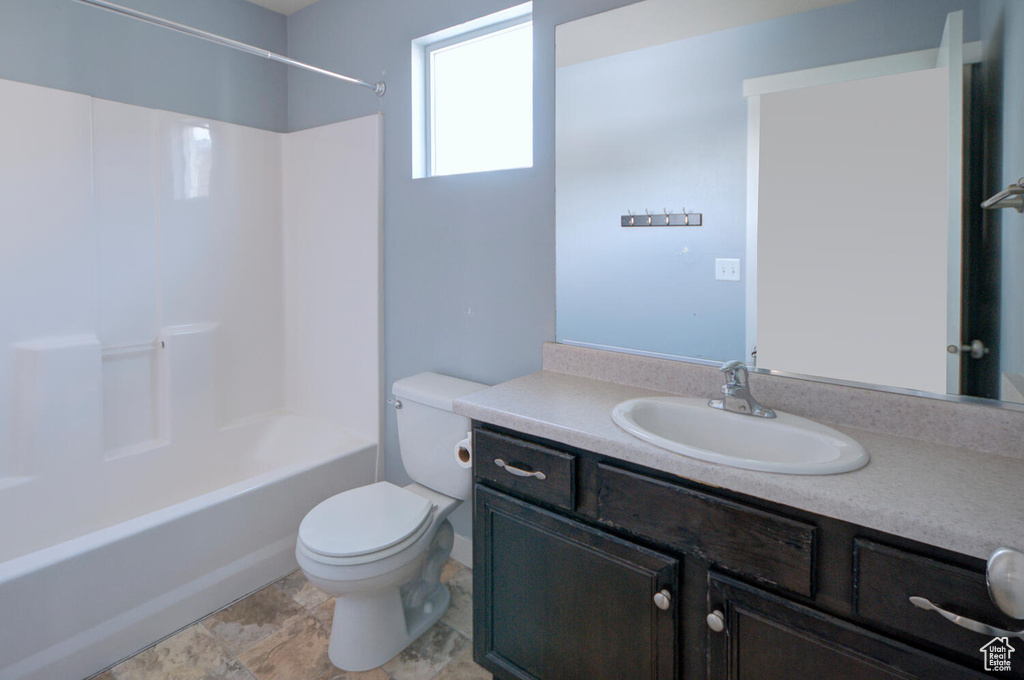 Full bathroom featuring tile floors, toilet, oversized vanity, and bathtub / shower combination