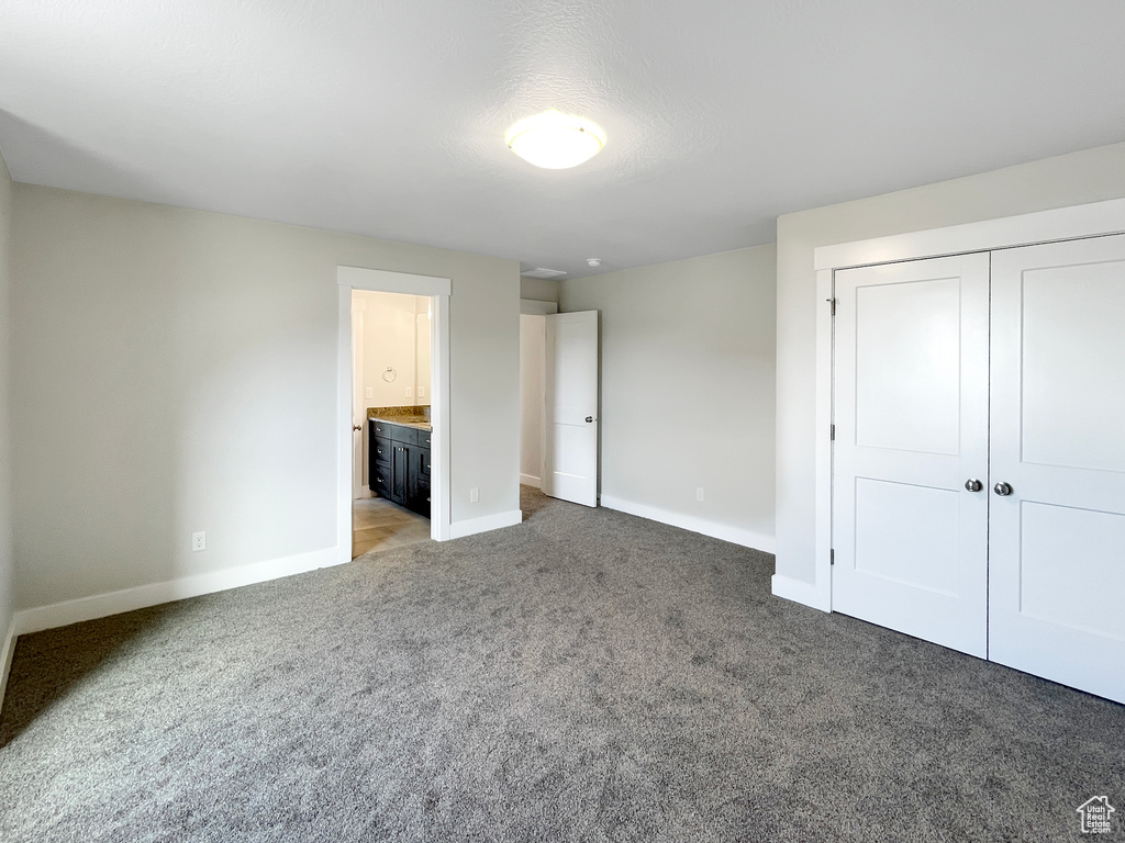Unfurnished bedroom featuring carpet flooring, ensuite bath, and a closet