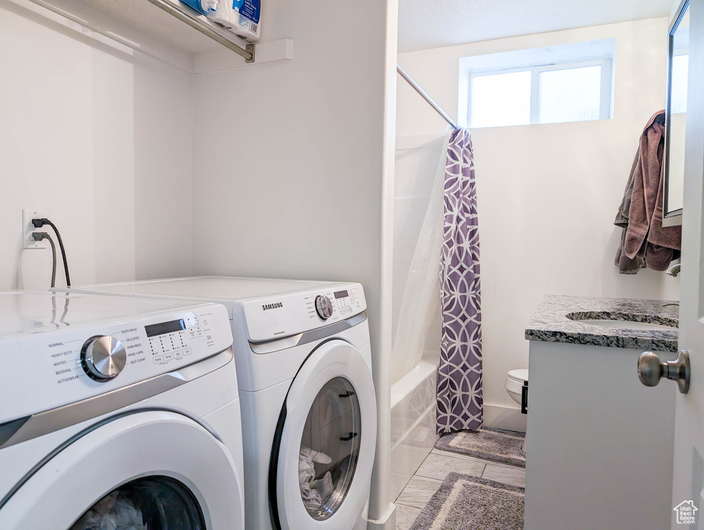Laundry area with light tile flooring and washer and clothes dryer