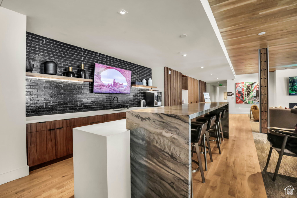 Bar with backsplash, sink, light hardwood / wood-style flooring, and wooden ceiling