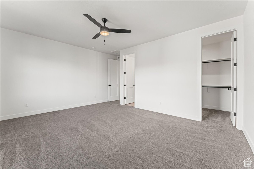 Unfurnished bedroom featuring light carpet, ceiling fan, a closet, and a walk in closet