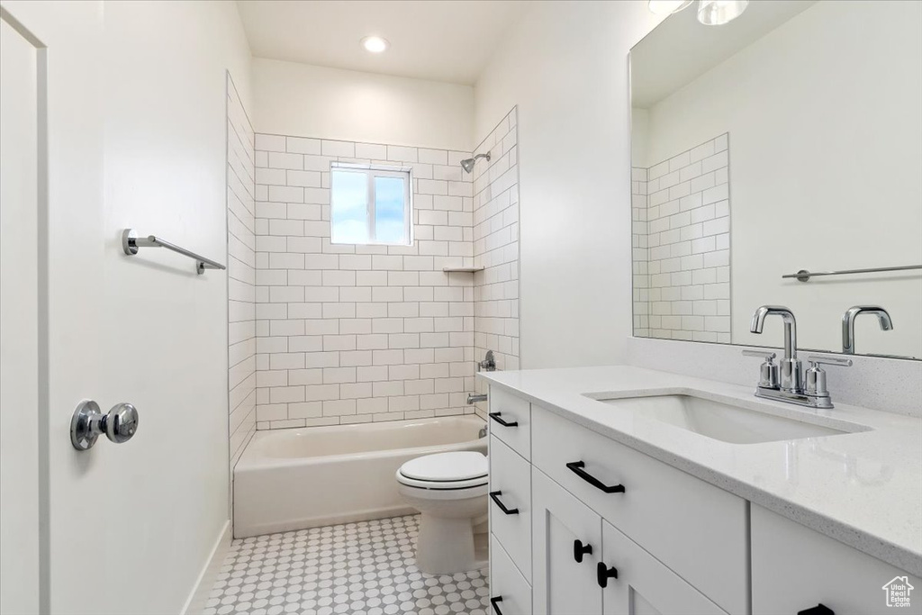 Full bathroom featuring vanity, toilet, tile flooring, and tiled shower / bath combo