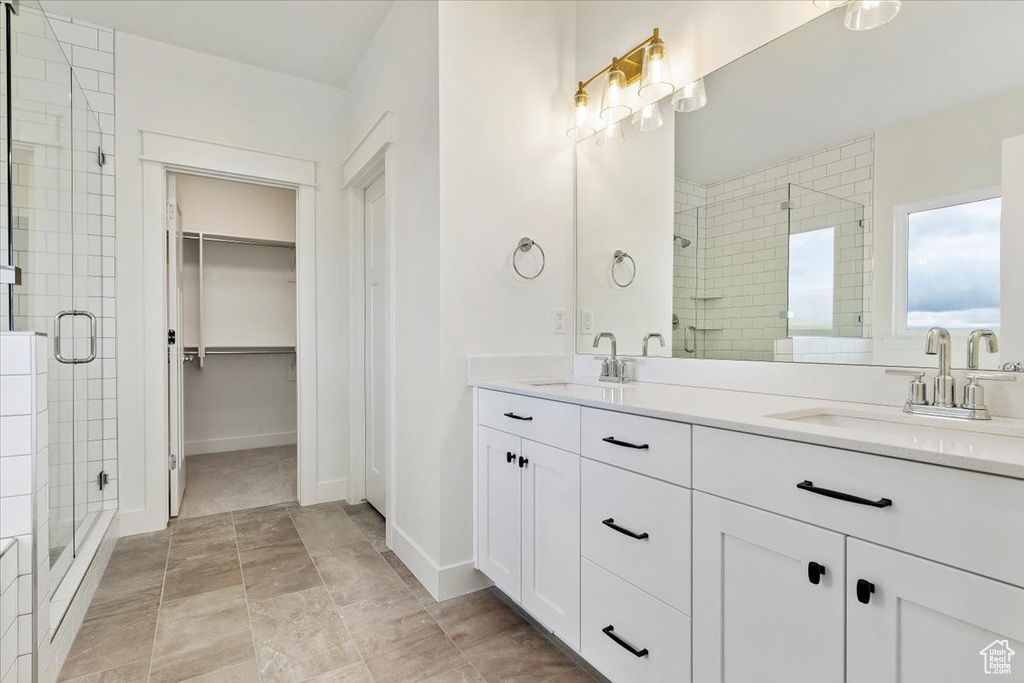 Bathroom featuring dual vanity, walk in shower, and tile floors
