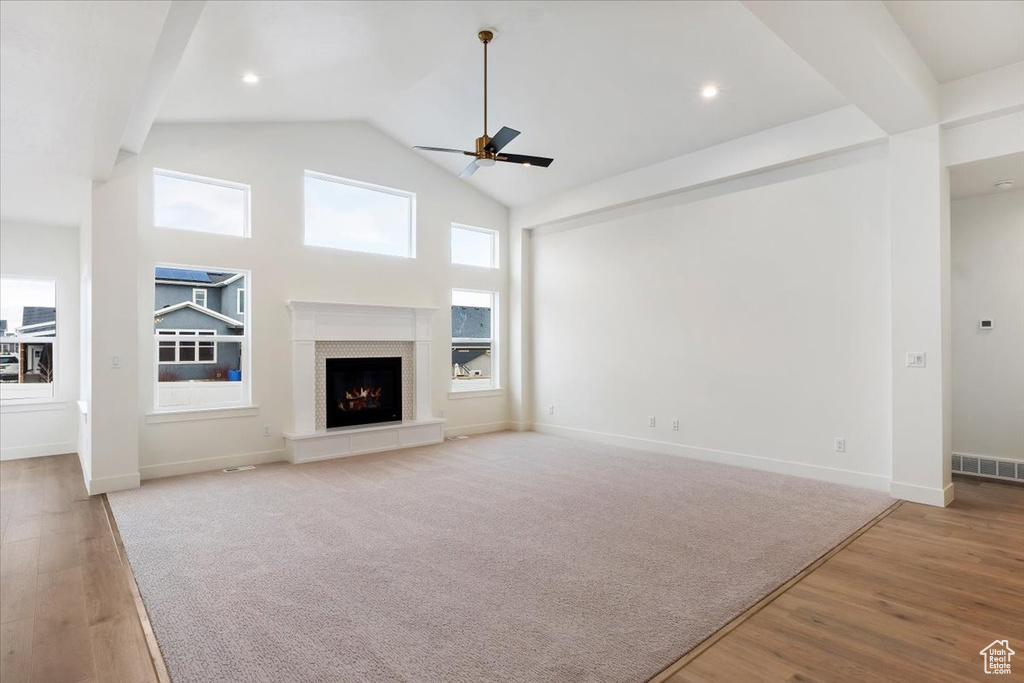 Unfurnished living room with high vaulted ceiling, light hardwood / wood-style floors, and ceiling fan