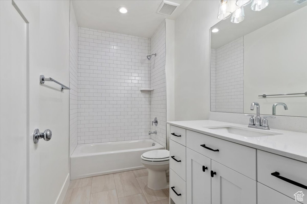 Full bathroom featuring tile flooring, tiled shower / bath, vanity with extensive cabinet space, and toilet