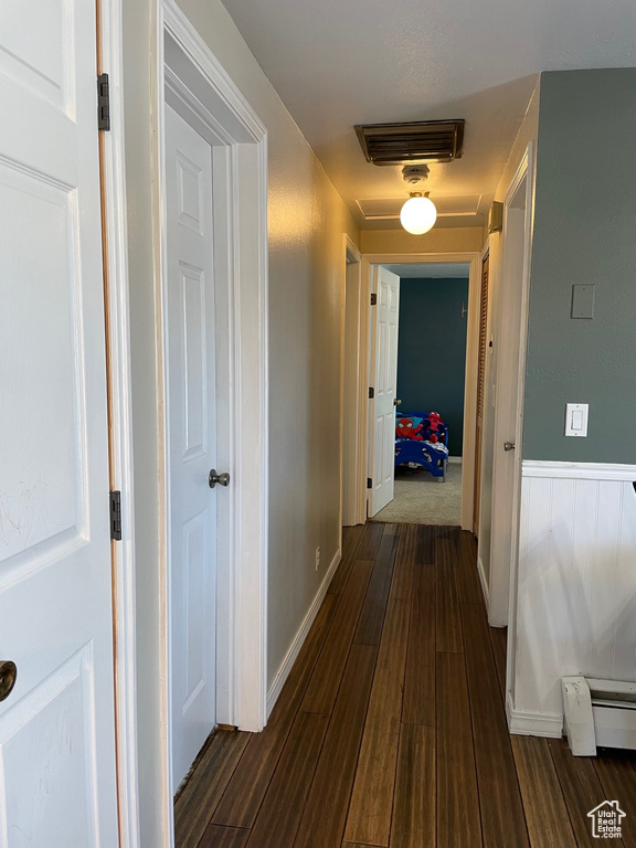 Hall featuring dark colored carpet and baseboard heating