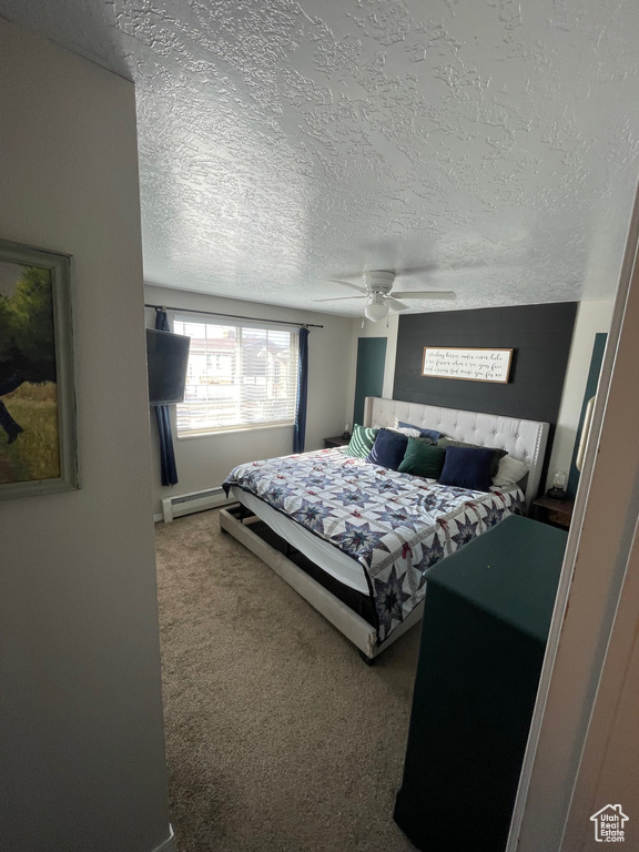 Carpeted bedroom featuring a textured ceiling, a baseboard heating unit, and ceiling fan