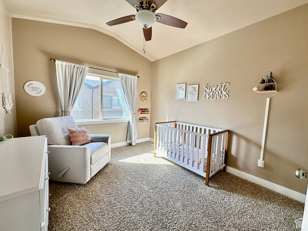 Bedroom with vaulted ceiling, light colored carpet, a nursery area, and ceiling fan