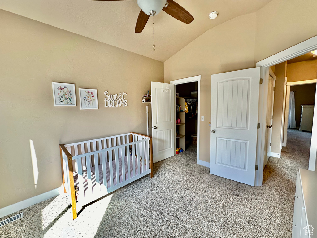 Bedroom featuring light carpet, a closet, ceiling fan, a nursery area, and lofted ceiling