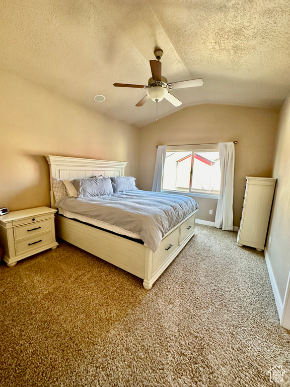 Carpeted bedroom with lofted ceiling, a textured ceiling, and ceiling fan