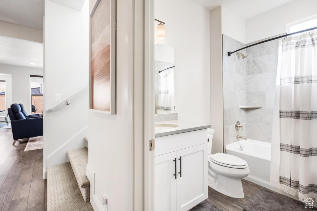 Full bathroom with vanity, toilet, a healthy amount of sunlight, and hardwood / wood-style floors