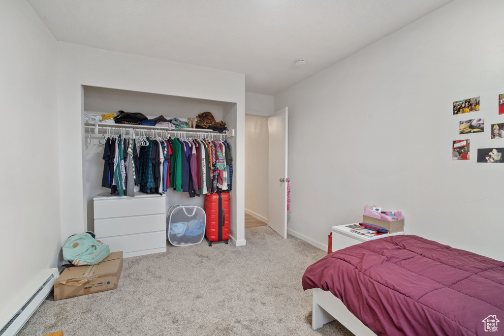 Carpeted bedroom with a baseboard heating unit and a closet