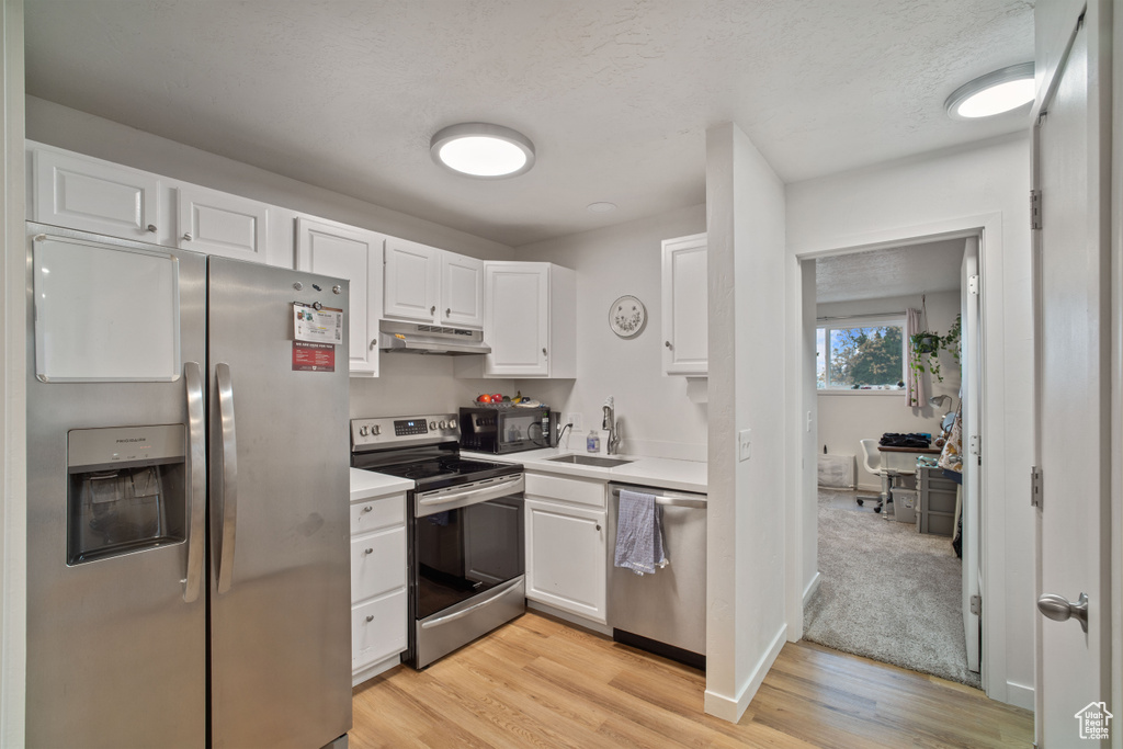 Kitchen with white cabinets, appliances with stainless steel finishes, and light colored carpet