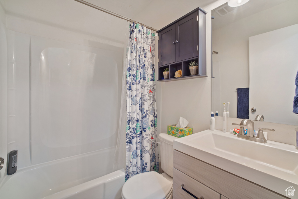 Full bathroom with toilet, shower / bath combo, and vanity with extensive cabinet space