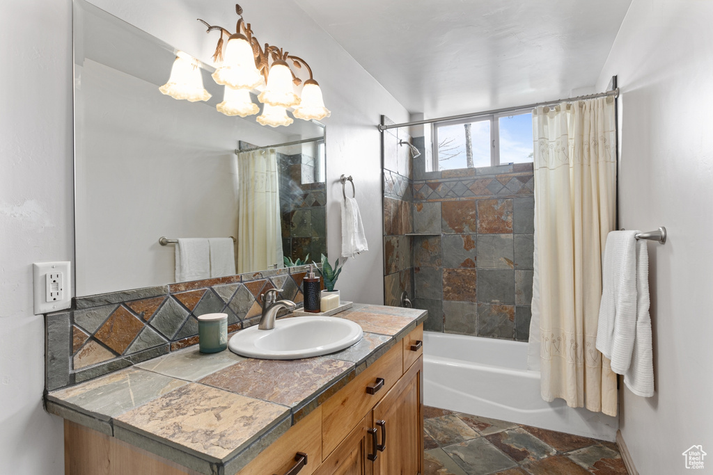 Bathroom with shower / bathtub combination with curtain, vanity with extensive cabinet space, tile floors, and a chandelier