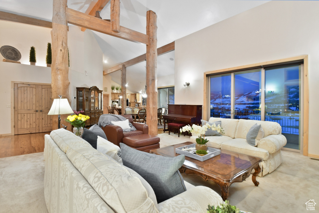 Living room with high vaulted ceiling, light colored carpet, and beam ceiling