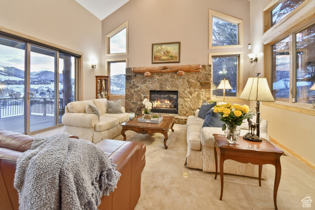 Carpeted living room featuring a mountain view, a fireplace, a high ceiling, and a healthy amount of sunlight